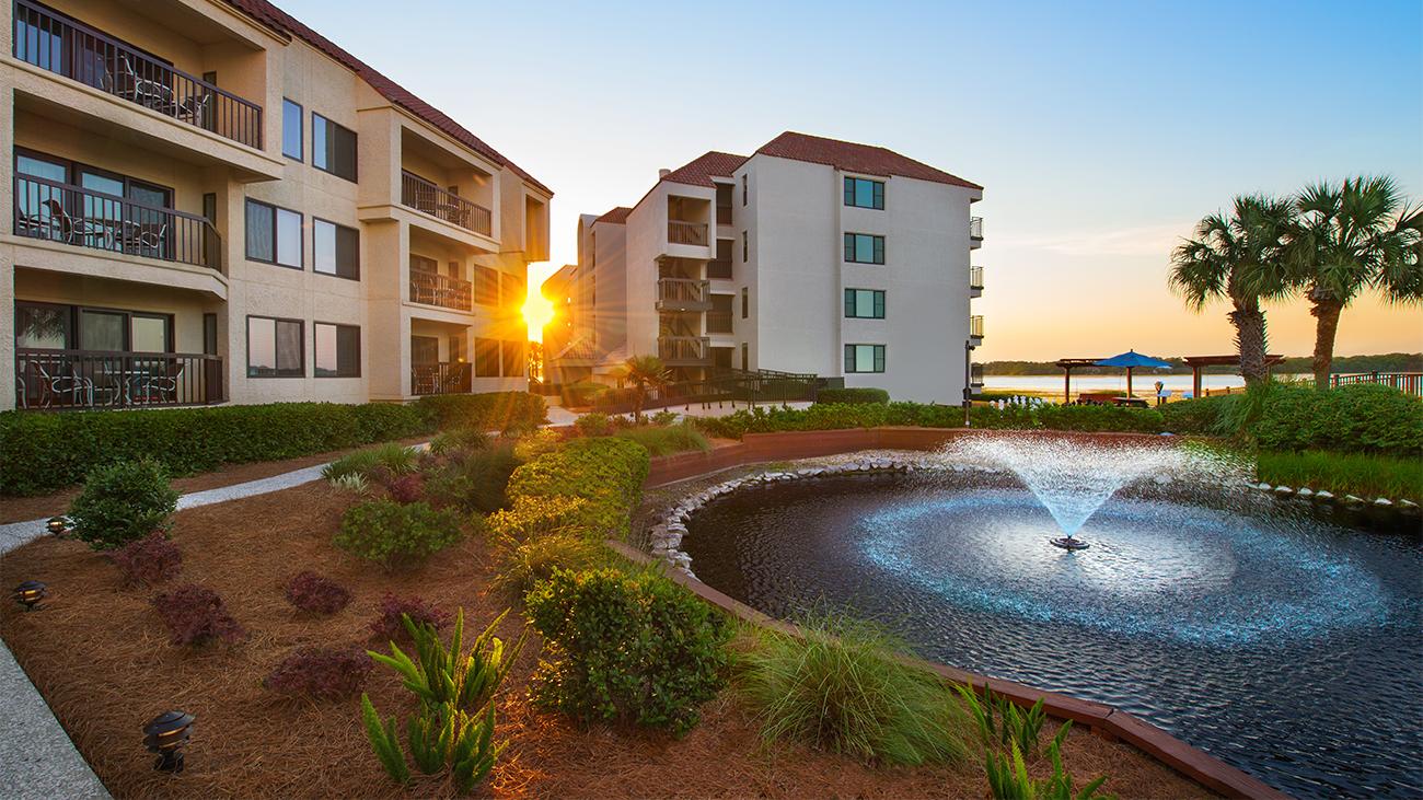 Exterior and grounds of Marriott's Sunset Pointe resort timeshare with pond fountain in foreground